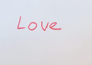 The word love, in red marker on a white background