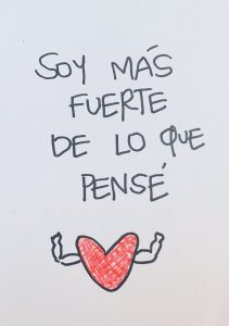 Red drawing of a heart with muscular arms. Above the drawing, black text reads SOY MAS FUERTE DE LO QUE PENSE